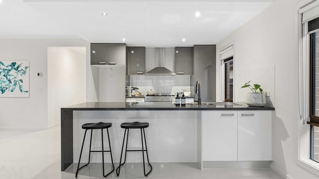 The kitchen is fitted with 40mm stone benchtops featuring a waterfall edge, 900mm stainless steel appliances and ample cupboard space.