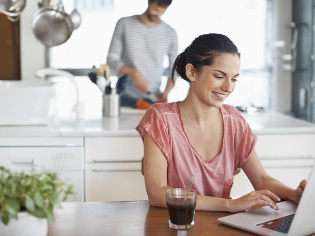 Generic shot of woman working on her laptop in the kitchen. Today's kitchens are more than just a food-prep zone, and have become spaces where we work and socialise. Free to use from iStock