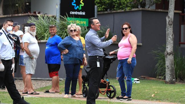 Officials from Centrelink speak to the lines of people at Southport. Picture: Adam Head