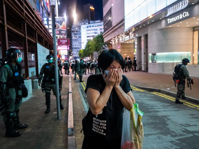 A woman covers her mouth as riot police fire pepper ball projectiles. Picture: Getty