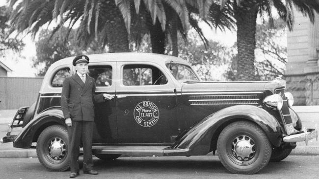 A uniformed driver of the All British Cab Service, waits for a fare in 1930s Sydney with his American 1935 Dodge car taxi.