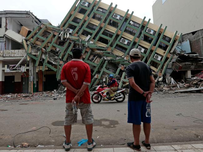 AFP PICTURES OF THE YEAR 2016: Men look at a destroyed building in the town of Portoviejo, Ecuador, on April 21, 2016 almost a week after a powerful quake hit the country. With hope of finding survivors fading Thursday, Ecuador began shouldering the cost of its devastating earthquake, announcing drastic economic measures to clean up the ruins of a tragedy that killed at least 570 people, with 5,733 injured. Scores of people are still missing. Photo: AFP/Juan Cevallos