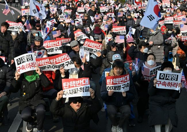 Supporters of impeached South Korea President Yoon Suk Yeol hold up anti-impeachment placards