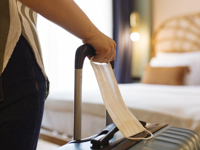 Woman with face mask and suitcase in the hotel room, close up.credit: iStockescape9 may 2021kendall hill