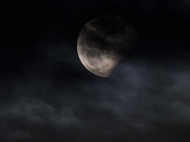 A partially eclipsed Moon obscured by clouds in Melbourne. Picture: Jake Nowakowski