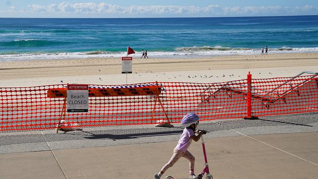 A young girl rides a scooter past a closed section of Surfers Paradise Beach on the Gold Coast. Picture: AAP