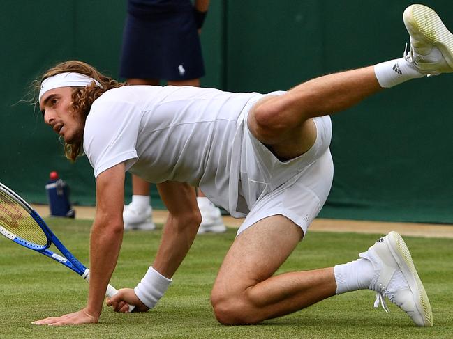 Greece's Stefanos Tsitsipas goes down as he returns against Italy's Thomas Fabbiano during their men's singles first round match on the first day of the 2019 Wimbledon Championships at The All England Lawn Tennis Club in Wimbledon, southwest London, on July 1, 2019. (Photo by Daniel LEAL-OLIVAS / AFP) / RESTRICTED TO EDITORIAL USE