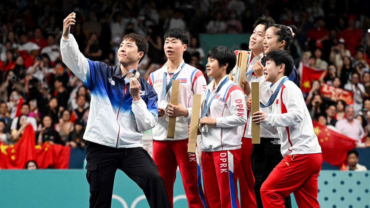 Bronze medallists South Korea’s Lim Jonghoon (L) takes a selfie picture with his mobile as he celebrates on the podium with: gold medallists China’s Wang Chuqin (rear R) and China’s Sun Yingsha (front L), silver medallists North Korea’s Ri Jong Sik (2nd L), and North Korea’s Kim Kum Yong (C) and bronze medallist and teammate South Korea’s Shin Yubin (rear R) at the end of their mixed table tennis doubles competition. Picture: Jung Yeon-je/AFP