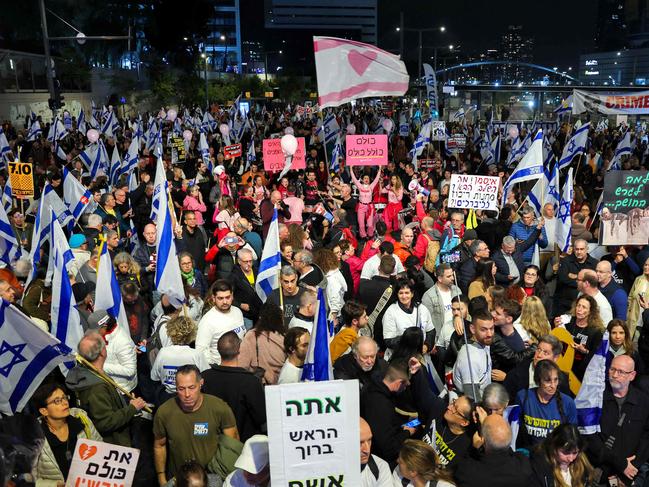 People hold placards and wave flags during an anti-government protest calling for action to secure the release of Israeli hostages held captive since the October 7 attacks by Palestinian militants in the Gaza Strip, in front of the Israeli Defence Ministry in Tel Aviv on December 21, 2024, amid the ongoing war between Israel and the militant Hamas group. (Photo by Jack GUEZ / AFP)