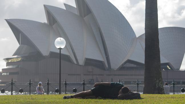 A lone reveller sleeps off the New Year’s Eve aftermath under the shadow of the Opera House. Picture: Thomas Lisson