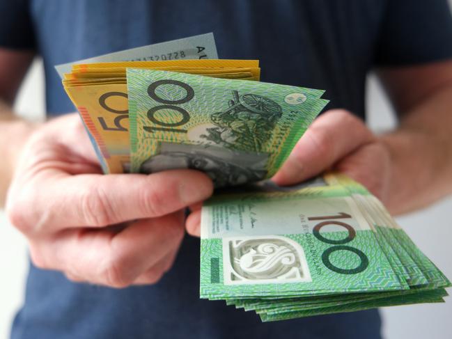 A man counting Australian dollar bills. A picture that describes buying, paying, handing out money, or showing money. Australian cash money generic