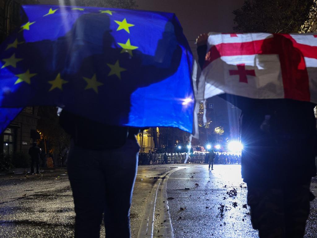 Protesters hold up a European Union and a Georgian flags during the fifth straight night of demonstrations against the government's postponement of EU accession talks until 2028, in central Tbilisi early on December 3, 2024. (Photo by Giorgi ARJEVANIDZE / AFP)