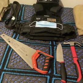 An image, taken before the video, shows the ballistics vest, knife, hammer and a saw laid out on a bed.