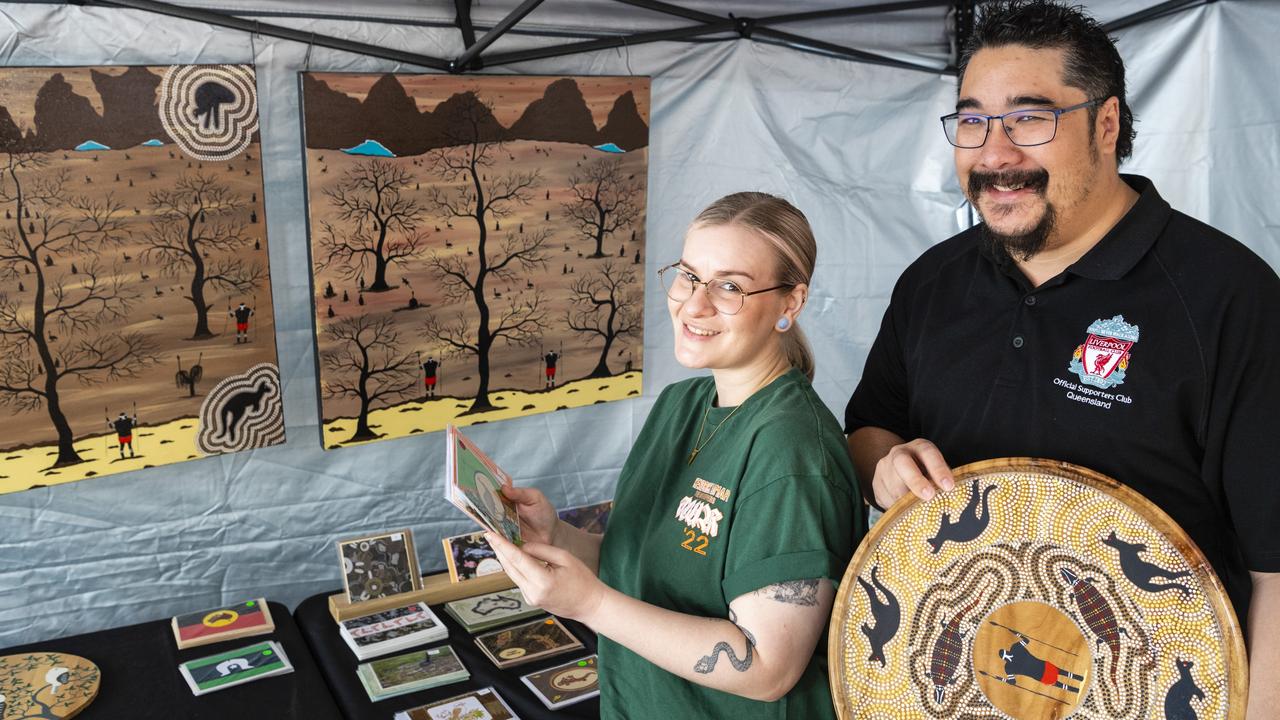 Ruth and Matt Yinn look over products by husband and wife duo Greg and Dee Locke (DG Murri Wood Art and Australian Indigenous Cards) at the Indigenous Artisan Markets at The Lighthouse, Saturday, December 17, 2022.