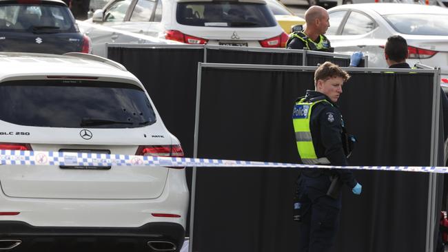 Police stand by the car, with a screen to conceal the dead man. Picture: David Caird