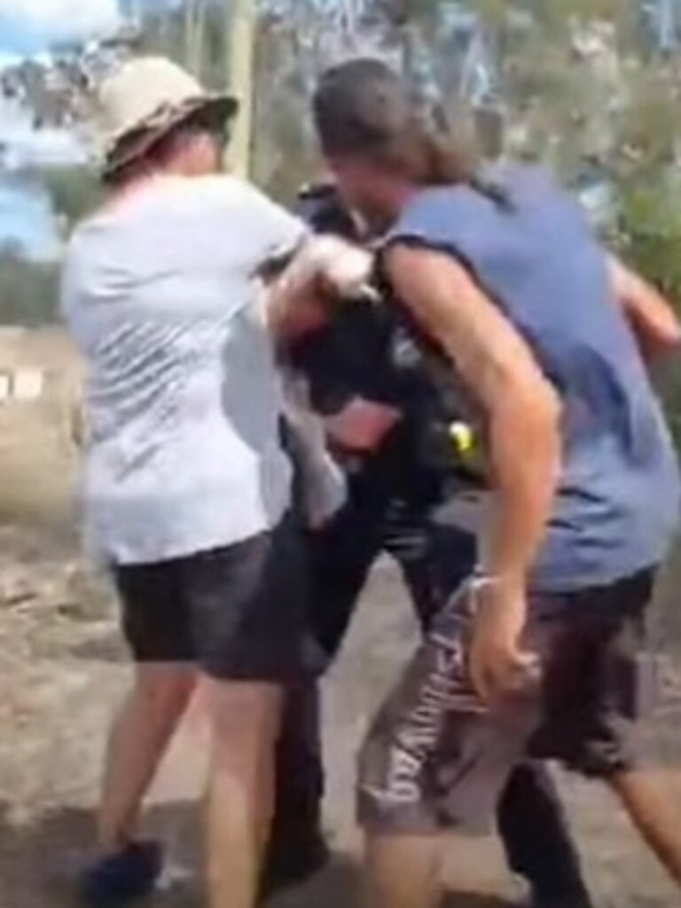 Police grapple with a protester near the “Gympie Pyramid” as a second protester rushes in.