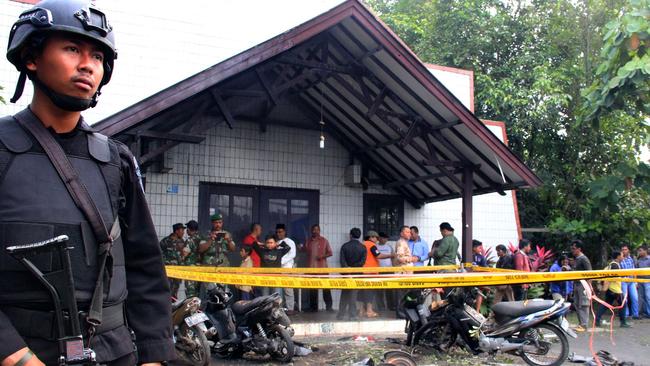 An Indonesian policeman stands guard outside the Oikume Church after a man allegedly threw molotov cocktails towards it. Picture: AFP