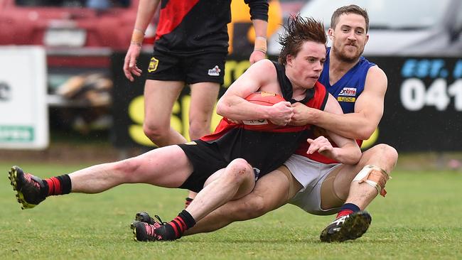 Riddell's Tommy Alkemade is wrapped up by a Diggers Rest opponent. Picture: Josie Hayden