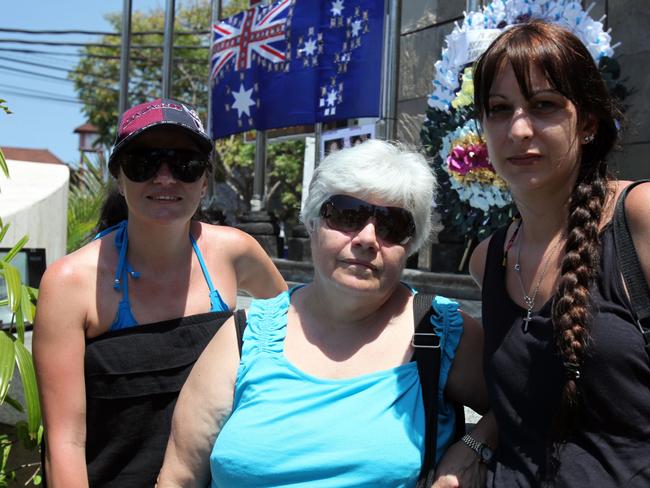 Maria Kotronoakis (left) with her mother Vicky and cousin Katie Parris place a flag with pictures of Elizabeth and Dimmy in Bali. Picture: Lukman Bintaro
