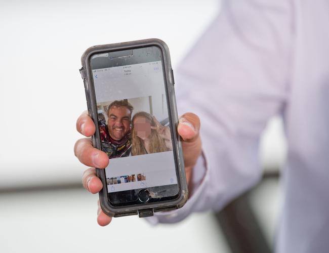 Jason Costigan shows media a selfie on his phone taken with the young woman at the centre of the harassment allegations made against him.