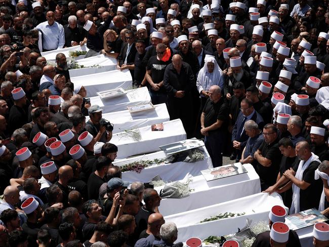 TOPSHOT - Druze elders and mourners surround the coffins of 10 of the 12 people killed in a rocket strike from Lebanon a day earlier, during a mass funeral in the Druze town of Majdal Shams in the Israel-annexed Golan Heights, on July 28, 2024. The Israeli military said the victims were struck by an Iranian-made rocket carrying a 50-kilogram warhead that was fired by Lebanese Hezbollah group at a soccer field in the Druze Arab town. Hezbollah has denied responsibility for the strike. (Photo by Jalaa MAREY / AFP)