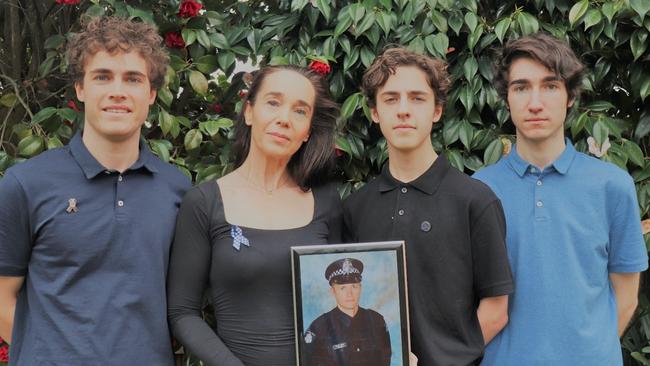 Sharron Mackenzie holds a photo of her beloved partner Kevin King alongside sons (left to right) James, Henry and William