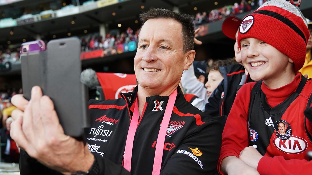 MELBOURNE, AUSTRALIA - JULY 06: Bombers head coach John Worsfold celebrates the win with fans with a selfie during the round 16 AFL match between the Essendon Bombers and the Sydney Swans at Melbourne Cricket Ground on July 06, 2019 in Melbourne, Australia. (Photo by Michael Dodge/Getty Images)