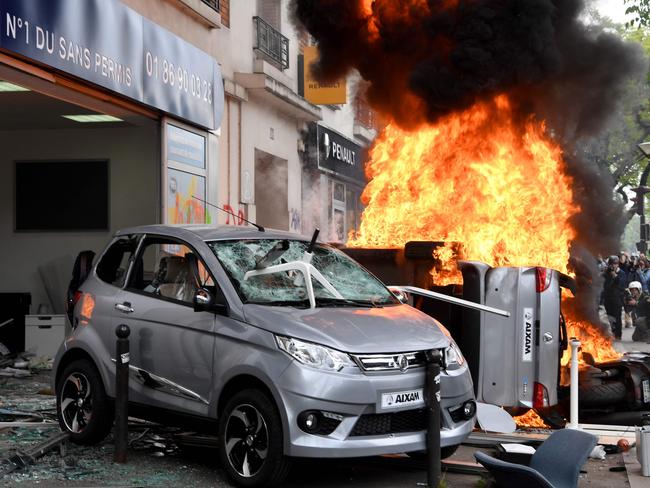 People look at a fire burning down a car and a motorbike during a demonstration on the side lines of the march for the annual May Day workers' rally, in Paris. Picture: AFP/Alain Jocard