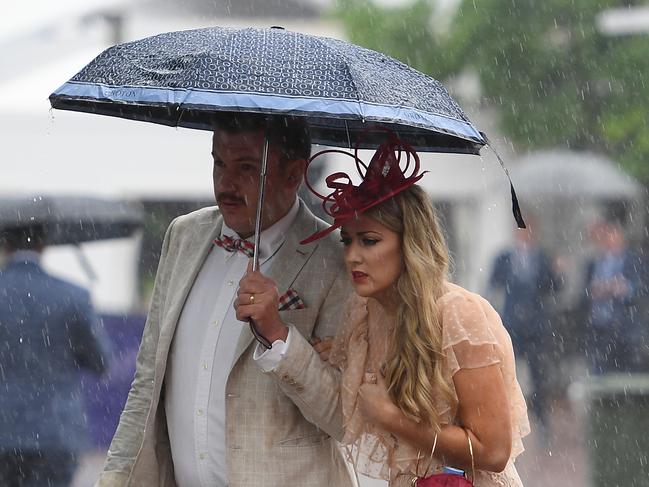 Racegoers are seen as heavy rain falls during the Lexus Melbourne Cup Day, as part of the Melbourne Cup Carnival, at Flemington Racecourse in Melbourne, Tuesday, November 6, 2018. (AAP Image/Dan Himbrechts) NO ARCHIVING, EDITORIAL USE ONLY
