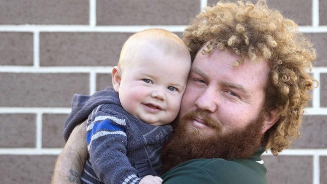 Toowoomba Dad Jeremi Simpson poses for a photograph with his son 7 month old Kaiden at home in Toowoomba, Saturday May 19, 2018. Jeremi is being hailed as a hero after taking down a knife wielding robber at Woolworths. (AAP/Image Sarah Marshall)