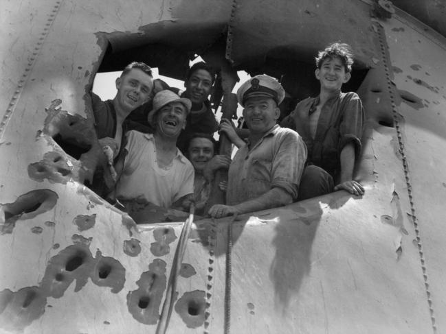 Members of the HMAS Sydney crew peer through a hole in the forward funnel. The damage was sustained in action against the Bartolomeo Colleoni. Picture: Peter Damien Parer / Supplied / Australian War Memorial