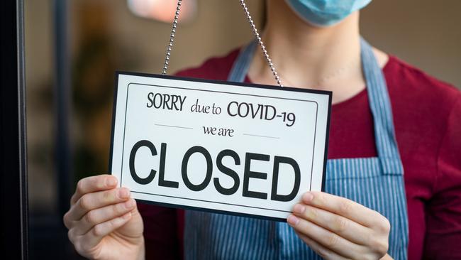 Businesswoman closing her business activity due to covid-19 lockdown. Owner with surgical mask close the doors of her store due to quarantine coronavirus damage. Close up sign of bankrupt business due to the effect of COVID-19 pandemic.