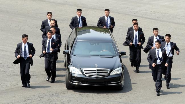 North Korean bodyguards jog next to a car carrying North Korea's leader Kim Jong Un returning to the North for a lunch break. Picture: AFP / Korea Summit Press Pool.