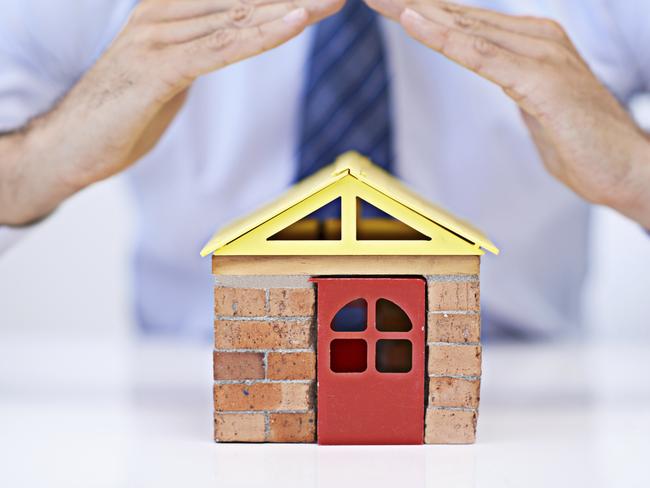 Cropped view of a young businessman's hands covering a small model house insurance, home, generic