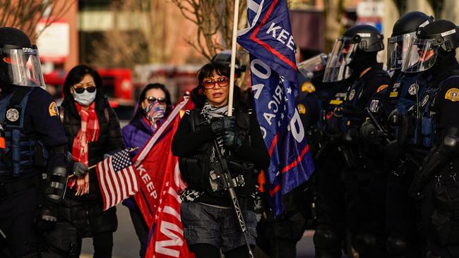 An armed supporter of President Donald Trump walks through a line of law enforcement personnel during a rally on December 12 in Olympia, Washington. Picture: AFP