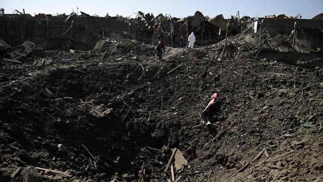 Afghan security forces stand near the crater from a truck bomb outside a foreign hotel.