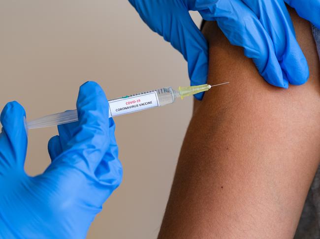 This picture depicts a young female clinician using a syringe to inject a concept COVD-19 liquid vaccine into a young girl patient during the Phase 3 vaccination human trials.