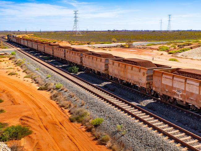 A freight train carrying iron ore travels along a rail track towards Port Hedland, Australia, on Monday, March 18, 2019. A two-day drive from the nearest big city, Perth, Port Hedland is the nexus of Australias iron-ore industry, the terminus of one of Australias longest private railways that hauls ore about 400 kilometers (250 miles) from the mines of BHP Group and Fortescue Metals Group Ltd. The line ran a record-breaking test train weighing almost 100,000 tons that was more than 7 kilometers long in 2001, and even normal trains haul up to 250 wagons of ore. Photographer: Ian Waldie/Bloomberg via Getty Images