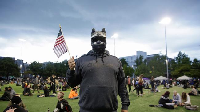 A man in a raccoon mask in an area being called the Capitol Hill Autonomous Zone (CHAZ) located around streets reopened to pedestrians after the Seattle Police Department's East Precinct was vacated in Seattle. Seattle's mayor told Donald Trump to "Go back to your bunker", escalating a spat after the president threatened to intervene over a police-free autonomous zone protesters have set up in the western US city.