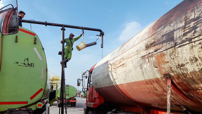 Workers in Semarang, Indonesia, transfer crude palm oil to tankers. Indonesia has now cancelled all palm oil exports. Picture: AFP