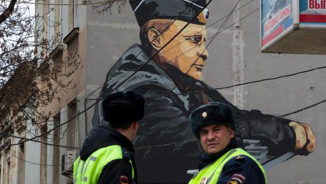 Police officers stand in front of graffiti depicting Russian President Vladimir Putin in Simferopol. Picture: AFP