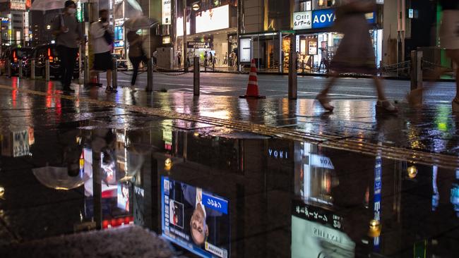 People walk on the Tokyo streets during a live broadcast of Prime Minister Yoshihide Suga. Picture: AFP