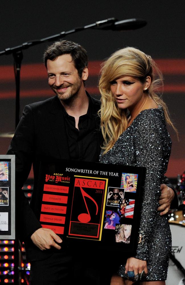 Dr. Luke has his arm around Kesha as they pose on stage in April at the ASCAP awards.