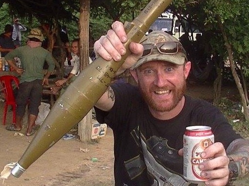 Mr Marchment holding a mortar and bear in Cambodia.