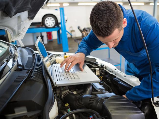 Generic mechanic using laptop on car at the repair garage. Townsville