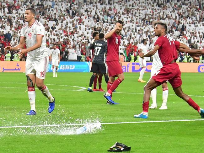 TOPSHOT - Fans throw bottles and flip-flops at the pitch during the 2019 AFC Asian Cup semi-final football match between Qatar and UAE at the Mohammed Bin Zayed Stadium in Abu Dhabi on January 29, 2019. (Photo by Giuseppe CACACE / AFP)