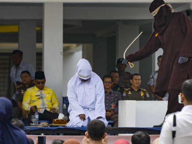 A woman is whipped in public by a member of the sharia police in Banda Aceh charged with breaking local Islamic law that outlaws public displays of affection. Picture: AFP