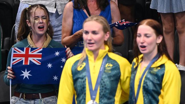 Gold medallist Mollie O'Callaghan, right, and silver medallist Ariarne Titmus pose on the podium at the Paris Olympics as Australia’s national anthem is played. Picture: AFP