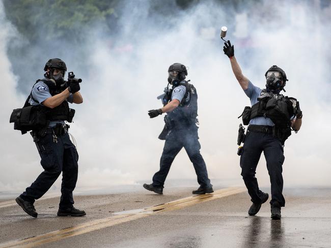 A police officer throws a tear gas canister towards protesters in Minneapolis. Picture: AP