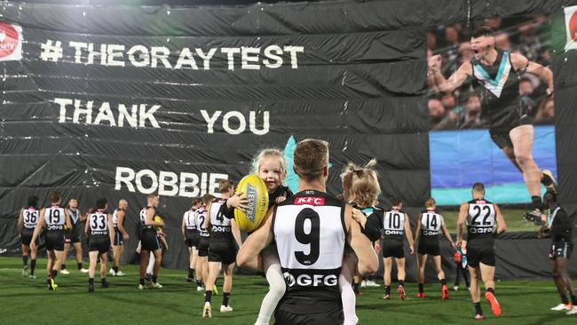 Gray’s kids joined him as he ran through the Port banner one last time. Picture: Sarah Reed/AFL Photos